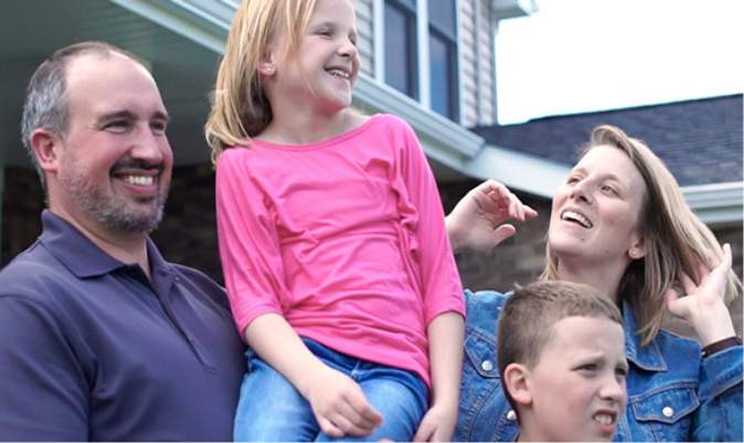 Family of four in front of home